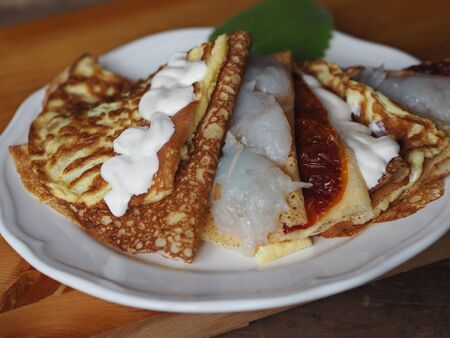 Pancakes stuffed with fish, scrambled eggs, tomatoes on a dark kitchen cutting board. A stack of pancakes. Background for Shrovetide. Seeing the winter, we meet spring.Place for text.の写真素材