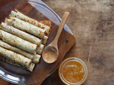 Pancakes with honey on a brown wooden rustic table. Pour pancakes with honey from a spoon....