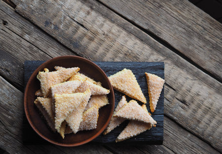 Homemade shortbread puff pastry triangle in a brown plate on a wooden ancient background. Top view....