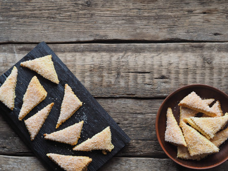 Homemade shortbread puff pastry triangle in a brown plate on a wooden ancient background. Top view....