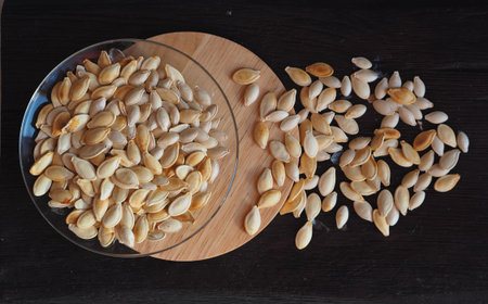 The benefits of pumpkin for human health. Pumpkin seeds on a dark wooden rustic background. Photo...