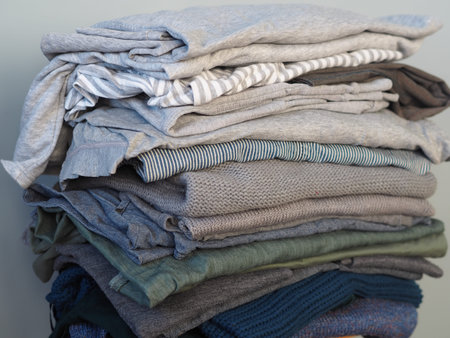 Warm knitwear stacked on a bench after washing. Store. Blue gray white tones. Gray background.