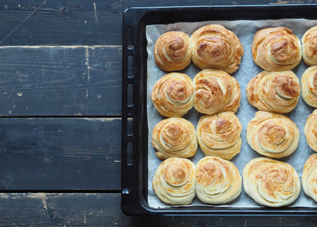 Homemade buns buns rich on a baking sheet from the kitchen oven on a dark wooden background. Holiday...