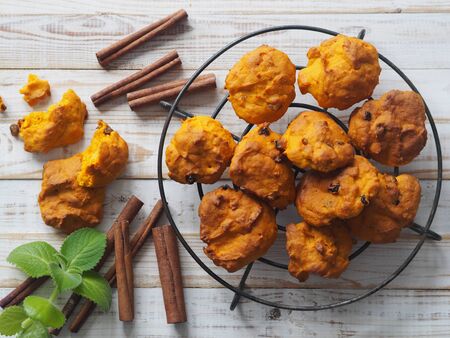 Pumpkin vegetarian or vegan cookies with raisins and cinnamon on a grid on a white wooden background. The view from the top.の写真素材