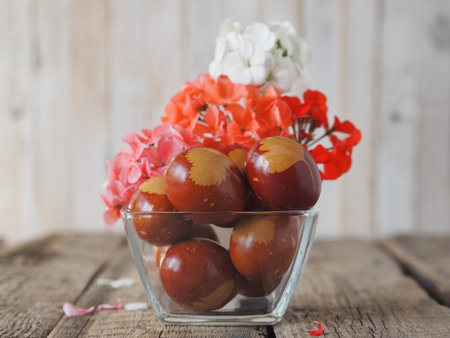 Easter background. Colored eggs in a glass plate with flowers on a wooden old background.