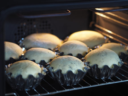 Buns are baked in baking pans in the kitchen oven. Homemade cake.