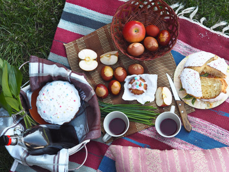 Spring picnic with Easter cakes, homemade wine and eggs. Easter feeding on the grass on the lawn in...