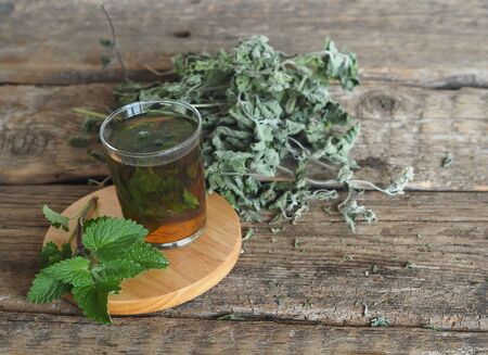 Use of the Melissa herb for medicinal purposes. Dried leaves of Melissa or mint with a fresh twig and decoction in a glass on an ancient wooden table.の写真素材