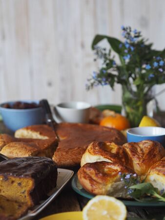 Food background. Home baking buns, cupcake, cakes and forget-me-not flowers on a wooden table with food.の写真素材