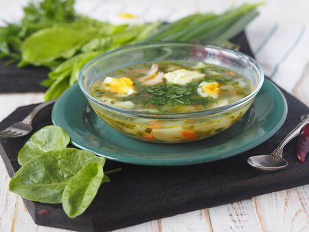 Healthy food.A bowl of spring green shavel soup against the background of a pile of green ingredients on a white wooden table.の写真素材