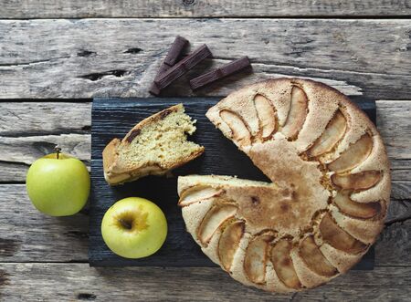 Round homemade Apple pie on a rustic wooden background. The view from the top.Dessert of dough with apples and chocolate for any holiday.の写真素材