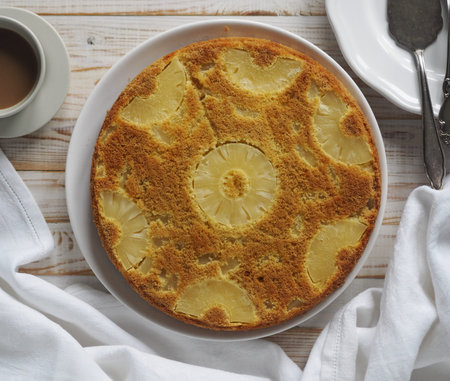 Pastry background. Round sponge cake with pineapple on a white wooden table. Healthy natural food.の写真素材