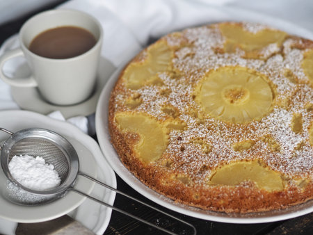 Sponge cake with pineapple on a dark wooden table. Home cooking.の写真素材