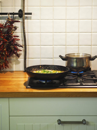 Healthy summer organic food. Fried eggs with tomatoes, tomatoes and herbs in a black pan on the...
