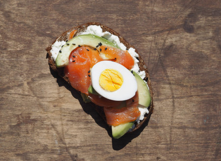 Healthy breakfast. Close-up of one whole grain bread sandwich with cream cheese, egg, avocado and...