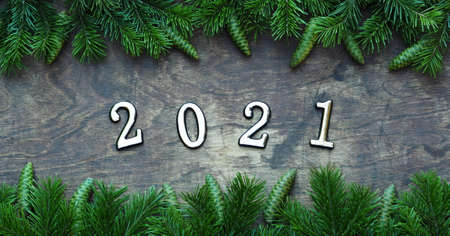 Happy New Year 2021. Branches of a Christmas tree are laid out on a wooden background. New year background with numbers 2021.の写真素材