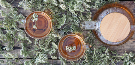 Medicinal herbs.Yarrow herbal tea in a glass teapot with a cup of honey on a wooden natural background.の写真素材