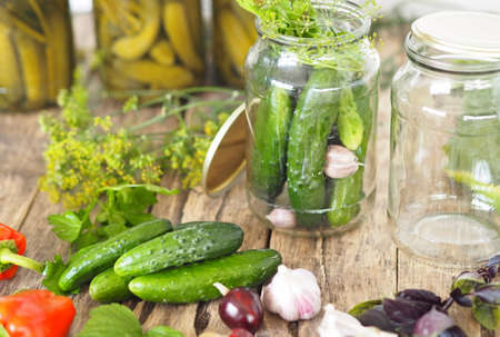 Home remedies for future use. Fresh and pickled cucumbers, homemade canned food with cucumbers in glass jars on a wooden background.の写真素材