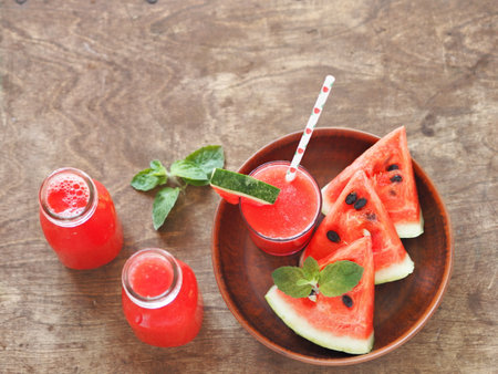 Juice with pulp or watermelon smoothie in glasses on a wooden background with watermelon slices.の写真素材