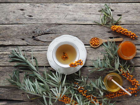 Sea buckthorn branches with berries, tea, honey and sea buckthorn jam on a wooden background. The season for harvesting medicinal sea buckthorn.の写真素材