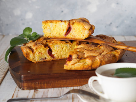 Apple summer seasonal charlotte pie with fresh apples and plums on a wooden kitchen board. Homemade...