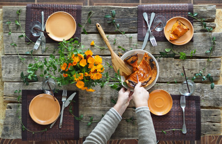 Thanksgiving wooden ancient table setting process. Hostess hands lay pumpkin on plates.Rustic style.