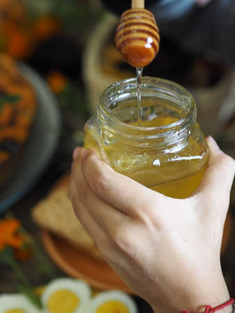 Thanksgiving Day. Liquid natural honey flowing from a skewer against the background of a served table. Healthy food.の写真素材
