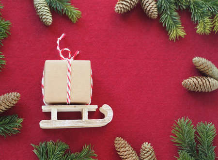 Congratulatory felt background with a gift box on wooden sledges, Christmas tree branches and pine cones. Place for text.Christmas or New Year background.の写真素材