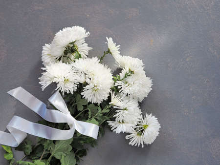 Bouquet of white chrysanthemums with a white ribbon bow. Country style with nature flower patternの写真素材