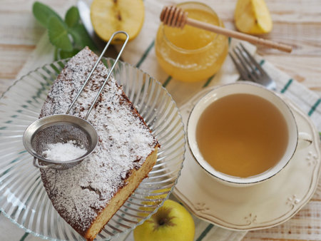 Piece of chocolate muffin sprinkled with powdered sugar on a light wooden table with tea. Homemade...