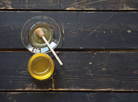 There is honey and a spoon with honey on a dark wooden background on a kitchen board. The idea of natural products.の写真素材