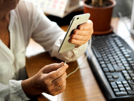 Working moments in handling the phone. Female hands connect the charger to a smartphone at a work...