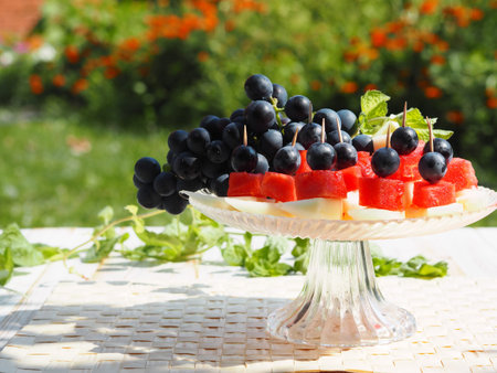 Food background from fresh fruits. Canapes of grapes, pieces of watermelon and melon on a natural green background. Healthy eating.の写真素材