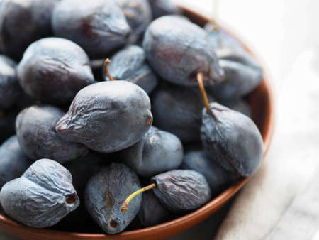 Harvesting season. Large autumn blue plums lie in a natural clay bowl. Natural fruits from the garden.の写真素材