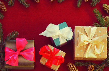 Christmas gifts are laid out on a felt red background surrounded by fir branches. Congratulatory New...