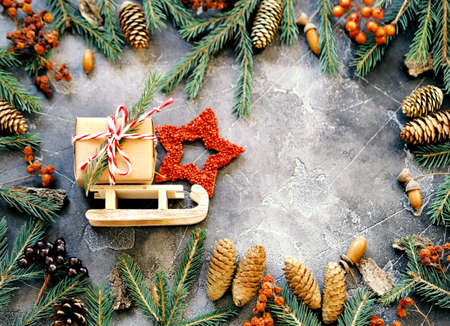 New Year is greetings on a dark wooden background. Toy sled with a gift box surrounded by fir branches. Copy space.の写真素材