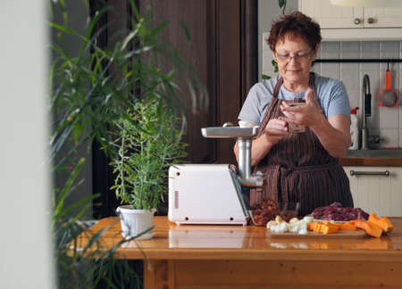 The process of decorating a house for Christmas. Fir branch, mini marshmallows in a mug with cocoa, a burning candle on the background of a wooden rustic table and the hands of an elderly woman.の写真素材