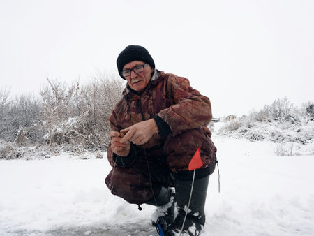 Winter fishing. A fisherman sits on a frozen river and catches fish in a drilled hole, an ice-hole....
