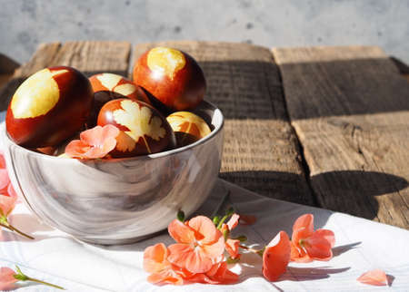 Eggs in a bowl on a wooden table in pelargonium or geranium flowers.の写真素材