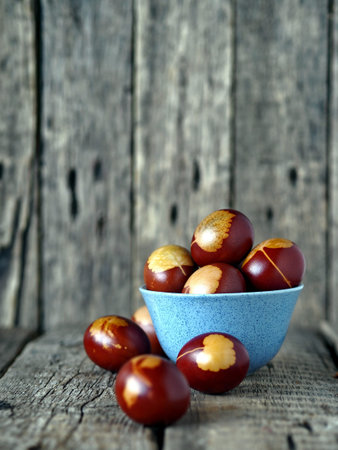 The idea of preparing for the Easter holiday. Painted eggs in a blue bowl on a wooden background.