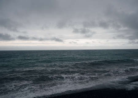 Dark natural background of inclement weather on the sea. Black sea and gray sky. Rain and waves. View from the wooden terrace on the beach.の写真素材