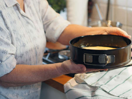 Home cooking. The hands of the older woman are busy preparing the cake. Healthy homemade food.の写真素材