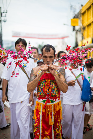 PHUKET, THAILAND - SEPTEMBER 30: Unidentified Mah song pierced weapon to their cheeks, They believed to suffer the pain of devotee during the Phuket Vegetarian Festival. The Festival is a famous annual festival also known as Nine Emperor Gods festival on のeditorial素材