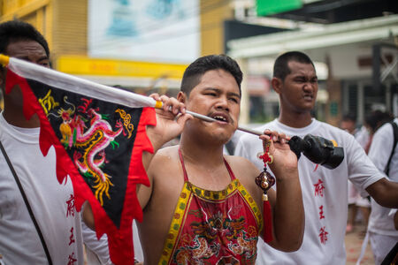 PHUKET, THAILAND - SEPTEMBER 30: Unidentified Mah song pierced weapon to their cheeks, They believed to suffer the pain of devotee during the Phuket Vegetarian Festival. The Festival is a famous annual festival also known as Nine Emperor Gods festival on のeditorial素材