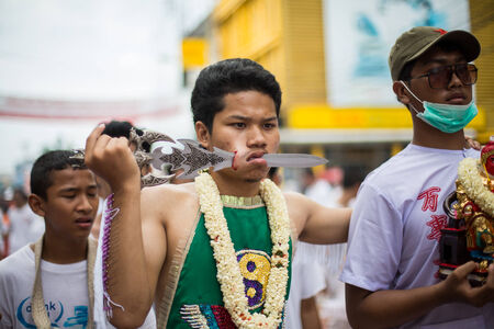 PHUKET, THAILAND - SEPTEMBER 30: Unidentified Mah song pierced weapon to their cheeks, They believed to suffer the pain of devotee during the Phuket Vegetarian Festival. The Festival is a famous annual festival also known as Nine Emperor Gods festival on のeditorial素材