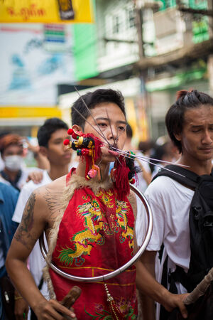PHUKET, THAILAND - SEPTEMBER 30: Unidentified Mah song pierced weapon to their cheeks, They believed to suffer the pain of devotee during the Phuket Vegetarian Festival. The Festival is a famous annual festival also known as Nine Emperor Gods festival on のeditorial素材