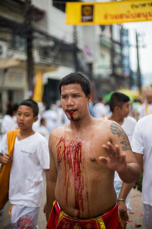 PHUKET, THAILAND - SEPTEMBER 30: Unidentified Mah song pierced weapon to their cheeks, They believed to suffer the pain of devotee during the Phuket Vegetarian Festival. The Festival is a famous annual festival also known as Nine Emperor Gods festival on のeditorial素材