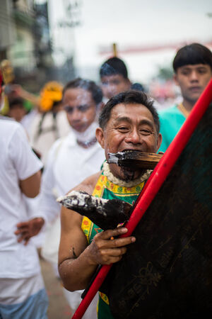 PHUKET, THAILAND - SEPTEMBER 30: Unidentified Mah song pierced weapon to their cheeks, They believed to suffer the pain of devotee during the Phuket Vegetarian Festival. The Festival is a famous annual festival also known as Nine Emperor Gods festival on のeditorial素材