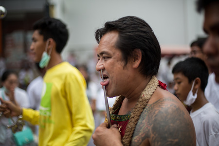 PHUKET, THAILAND - SEPTEMBER 30: Unidentified Mah song pierced weapon to their cheeks, They believed to suffer the pain of devotee during the Phuket Vegetarian Festival. The Festival is a famous annual festival also known as Nine Emperor Gods festival on のeditorial素材