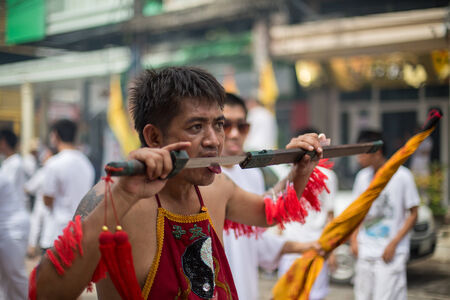 PHUKET, THAILAND - SEPTEMBER 30: Unidentified Mah song pierced weapon to their cheeks, They believed to suffer the pain of devotee during the Phuket Vegetarian Festival. The Festival is a famous annual festival also known as Nine Emperor Gods festival on のeditorial素材